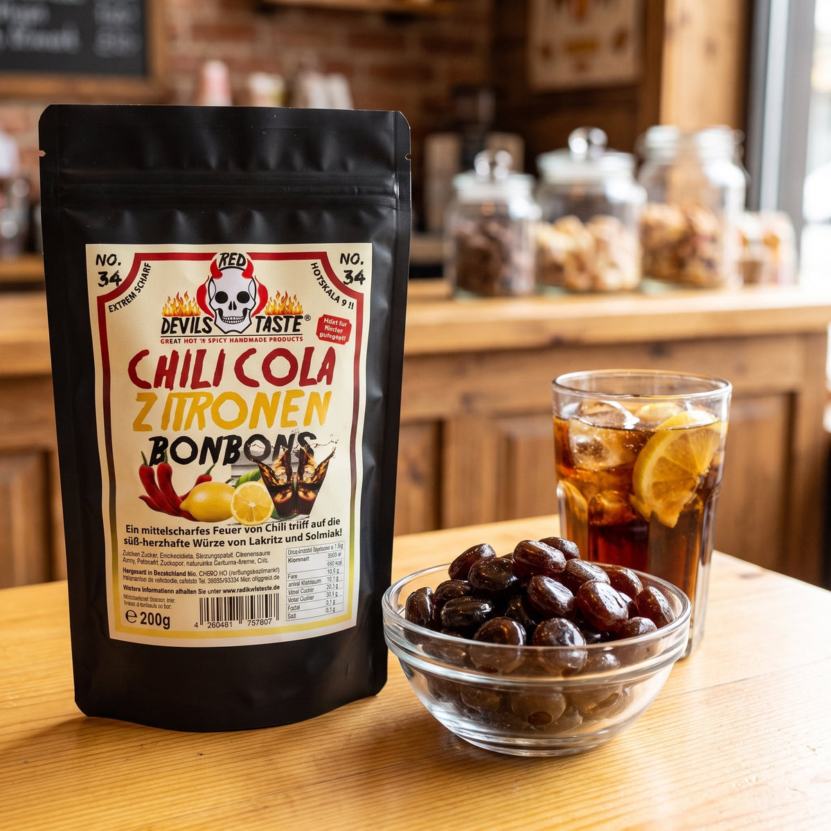 Chili Cola Zitronen Bonbons Beutel neben einer Schale Bonbons und einem Glas Cola