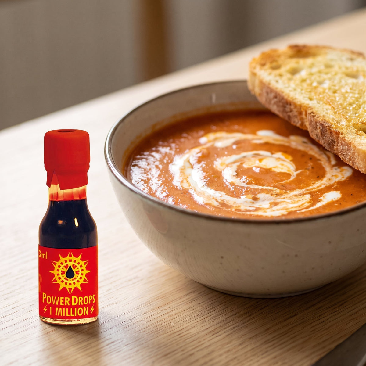 Scovilla Power Drops 1 Million Scoville Chili-Extrakt neben einer Schale Tomatensuppe