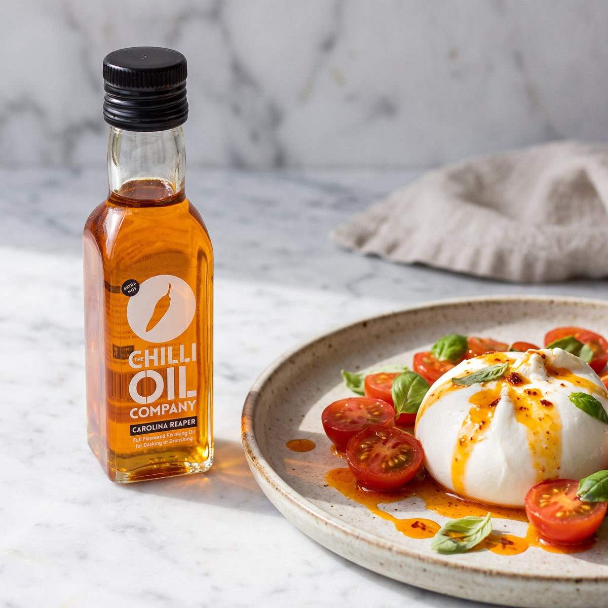 Carolina Reaper Chili-Öl neben Burrata mit Tomaten und Basilikum