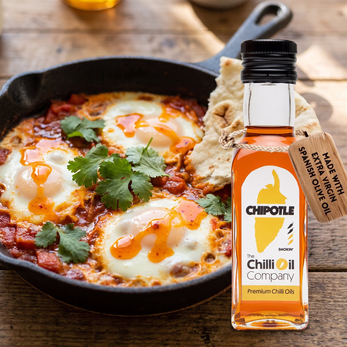 Chipotle Morita Chili-Öl neben einer Pfanne Shakshuka mit pochierten Eiern und Fladenbrot