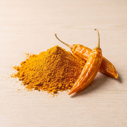 Aji Amarillo Chilipulver mit getrockneten Aji-Amarillo-Schoten auf Holzuntergrund