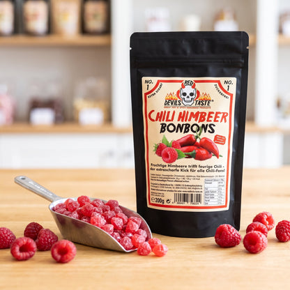 Chili Himbeer Bonbons Beutel neben einer Schaufel roter Bonbons und frischen Himbeeren