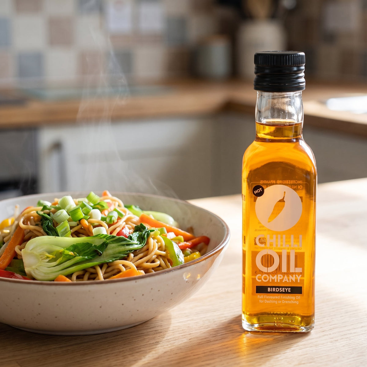 Bird's Eye Chili-Öl neben einer Schale Bratnudeln mit Gemüse