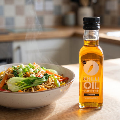Bird's Eye Chili-Öl neben einer Schale Bratnudeln mit Gemüse