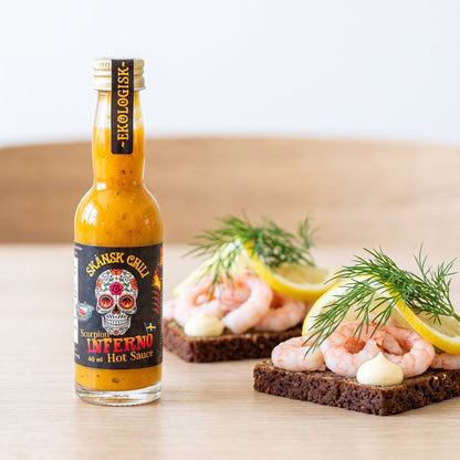 Skånsk Chili Scorpion Inferno Hot Sauce neben skandinavischen Broten mit Crevetten und Dill