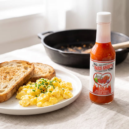 Marie Sharp's Hot Habanero Sauce neben Rührei mit Schnittlauch und geröstetem Sauerteigbrot