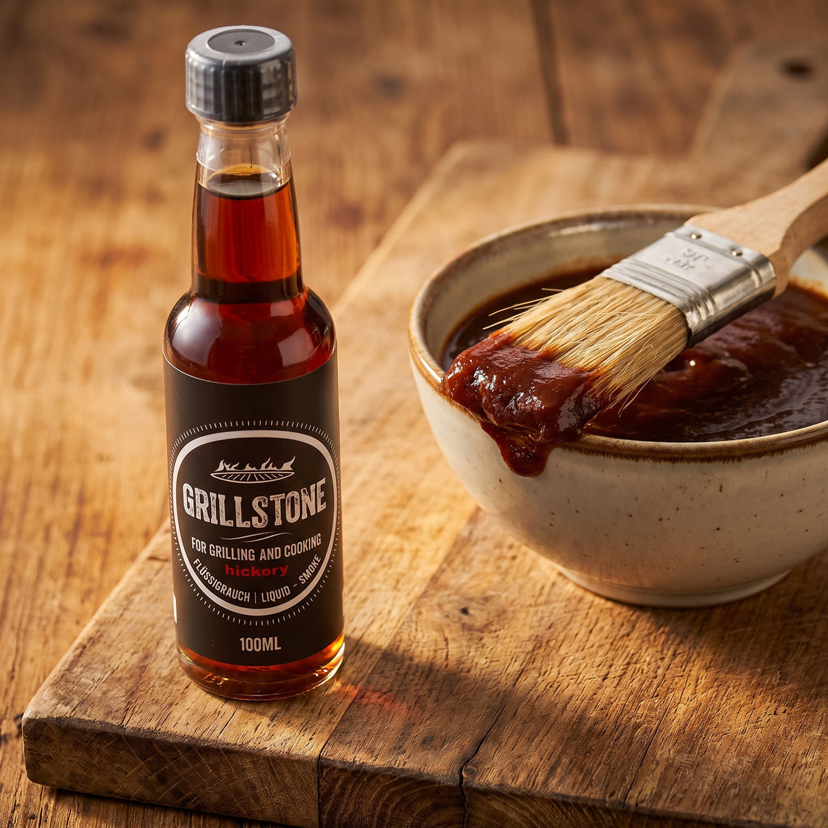 Grillstone Liquid Smoke Hickory neben einer Schüssel BBQ-Sauce mit Pinsel