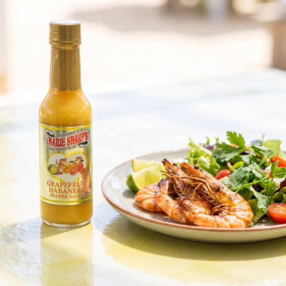 Marie Sharp's Grapefruit Pulp Habanero Sauce neben gegrillten Crevetten mit Limette und Salat
