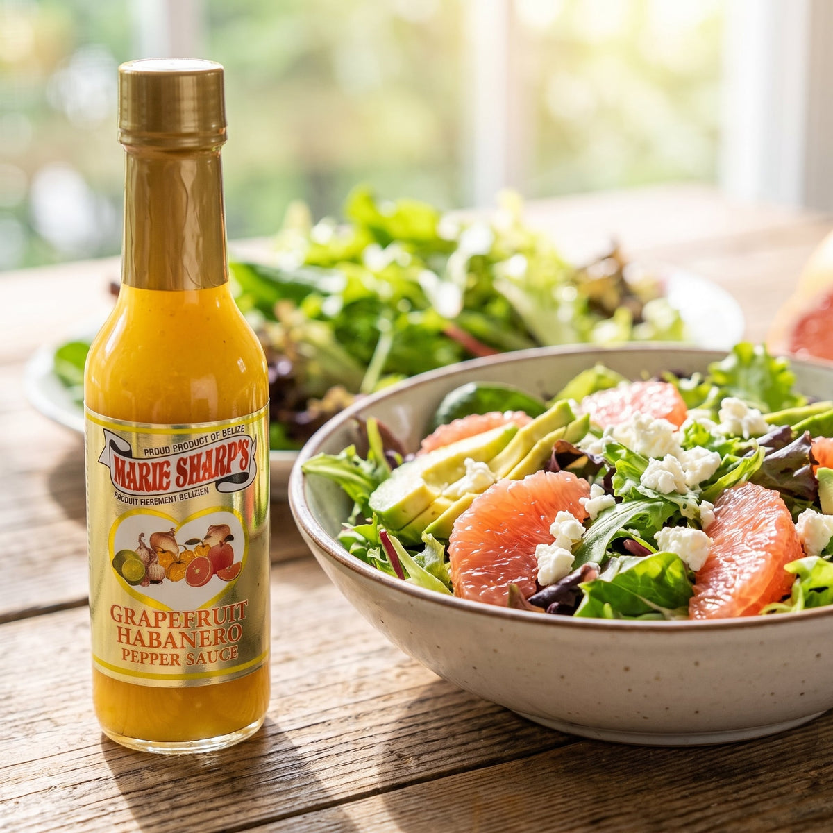 Marie Sharp's Grapefruit Pulp Habanero Sauce neben einem Salat mit Avocado, Grapefruit und Feta