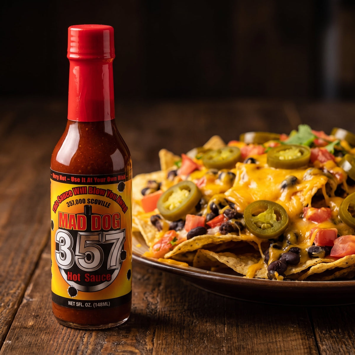 Mad Dog 357 Hot Sauce neben einem Teller Nachos mit Käse und Jalapenos
