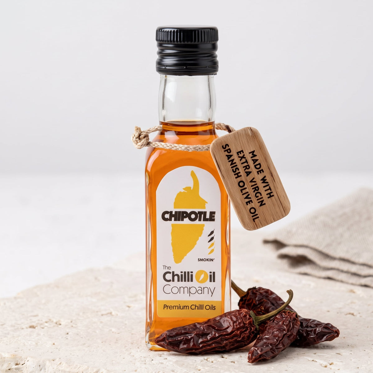 Chipotle Morita Chili-Öl mit Holzanhänger neben getrockneten Chipotle-Morita-Schoten