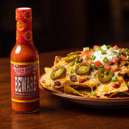Marie Sharp's Beware Habanero Sauce neben einem Teller Nachos mit Käse und Sauerrahm