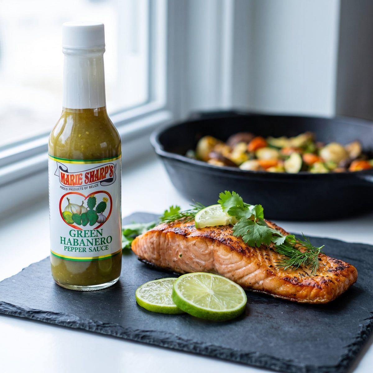Marie Sharp's Green Nopal Habanero Sauce neben gegrilltem Lachsfilet mit Limette und Kräutern