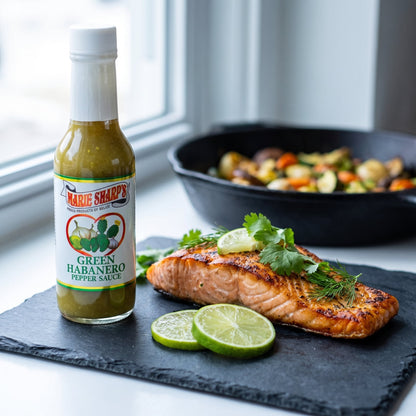 Marie Sharp's Green Nopal Habanero Sauce neben gegrilltem Lachsfilet mit Limette und Kräutern